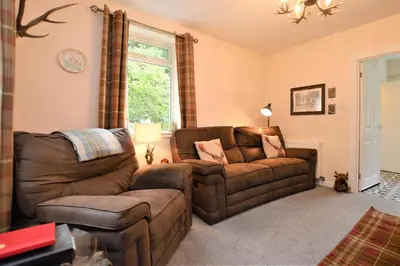 a living room with a couch and a chair at Nursery Cottage Benmore in Benmore