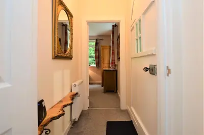 a hallway with a door and a mirror on the wall at Nursery Cottage Benmore in Benmore