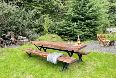 a picnic table and two benches in the grass at Nursery Cottage Benmore in Benmore