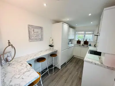 a kitchen with white cabinets and a marble counter top at Cosy Cottage in Stirling