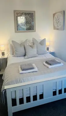 a white bed with two towels on top of it at Cosy Cottage in Stirling