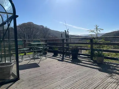 a wooden deck with a table and chairs and a fence at Spacious lodge with king sized bed in Inveraray