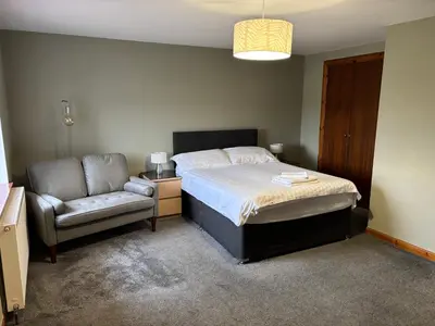 a bedroom with a bed and a couch and a chair at The Barn Lodge in Stirling