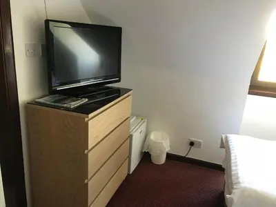 a room with a television on a dresser with a bed at The Barn Lodge in Stirling