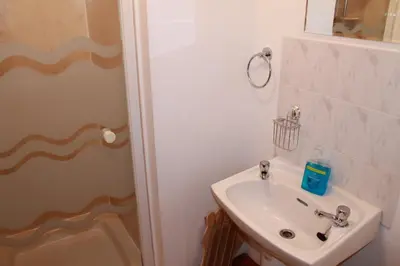 a white bathroom with a sink and a shower at The Barn Lodge in Stirling