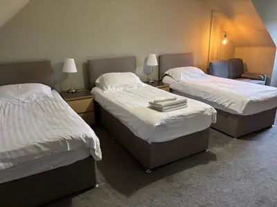 two beds in a room with two chairs and lamps at The Barn Lodge in Stirling