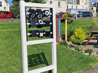 a sign in the grass in a yard at Coorie Braw Cottage in Kirn