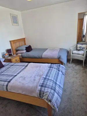 a bedroom with two beds and a chair at Coorie Braw Cottage in Kirn