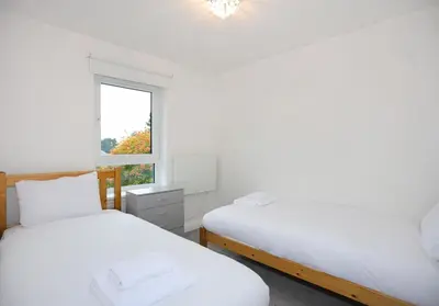 two beds in a white room with a window at The South Maybury Residence in Edinburgh