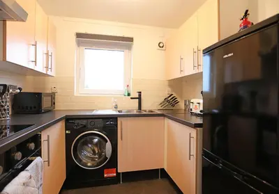 a kitchen with a washer and a sink and a dishwasher at The South Maybury Residence in Edinburgh