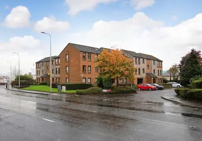 a wet street with buildings on a rainy day at The South Maybury Residence in Edinburgh