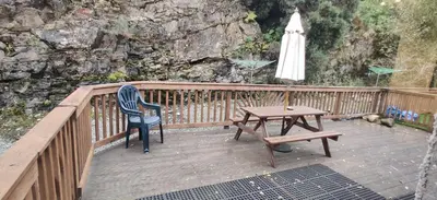 a wooden deck with a table and an umbrella at The Cobbler Cottage - Loch Lomond and Arrochar Alps in Arrochar
