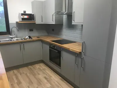 a kitchen with white cabinets and a wooden counter top at The Stables near Glasgow in Balmore