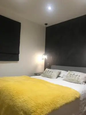 a bedroom with a large bed with a yellow blanket at The Stables near Glasgow in Balmore