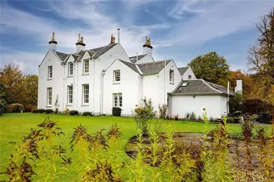 a large white house with a green yard at Park of Drumquhassle in Glasgow