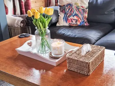 a coffee table with a vase of flowers and a candle at Chalet Loch Leven Lodge 12 by Interhome in Kinross