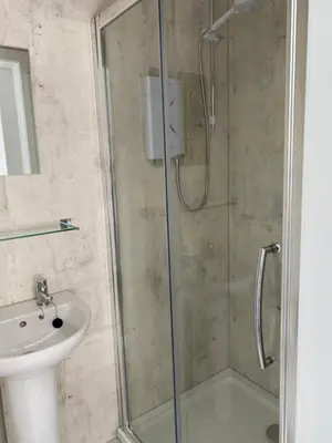 a shower with a glass door next to a sink at West Loch House in West Tarbert