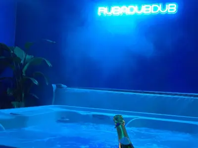 a bottle of beer sitting in a bath tub with a neon sign at The NEW Blue Horse Suite at The Grumpy Schnauzer B&B Luxury Private Indoor Hot Tub Breakfast in Bed in Airdrie