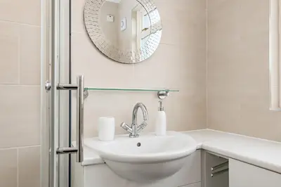 a white bathroom with a sink and a mirror at Balmoral Residence 30 mins from Edinburgh and Glasgow in Falkirk