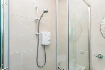 a shower with a shower head in a bathroom at Balmoral Residence 30 mins from Edinburgh and Glasgow in Falkirk