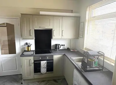 a kitchen with white cabinets and a stove top oven at Balmoral Residence 30 mins from Edinburgh and Glasgow in Falkirk