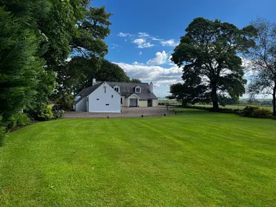 a large white house on a grassy field at Whitehouse in Uplawmoor
