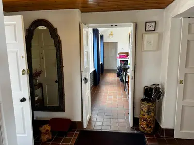 a hallway with a mirror and a tile floor at Whitehouse in Uplawmoor
