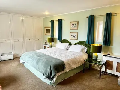 a bedroom with a large bed with blue curtains at Whitehouse in Uplawmoor