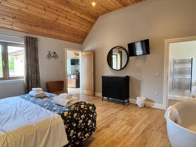a bedroom with a bed and a mirror and a tub at Osprey Lodge 8 with Hot Tub in Newton Stewart