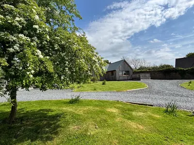 a gravel driveway with a barn and a tree at Osprey Lodge 8 with Hot Tub in Newton Stewart