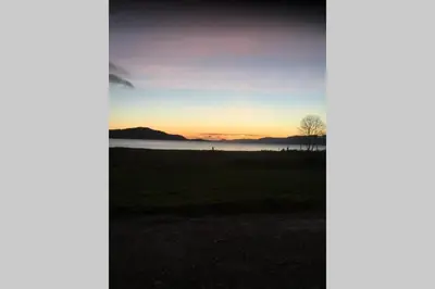 a tree in a field with the sunset in the background at Sea Breeze Pod in Fort William
