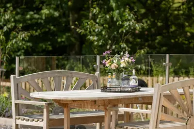 a wooden table with a vase of flowers on it at Slatehouse Cottage, Drumlanrig in Thornhill