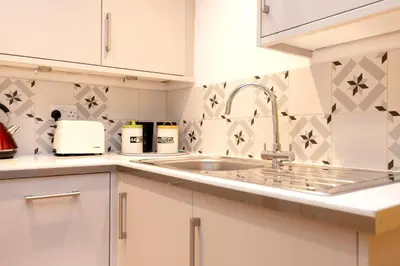 a kitchen with white cabinets and a sink at JOIVY Charming Home with Patio Nearby the Castle in Edinburgh