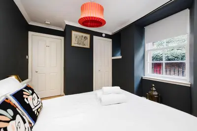 a bedroom with a white bed and a window at JOIVY Charming Home with Patio Nearby the Castle in Edinburgh