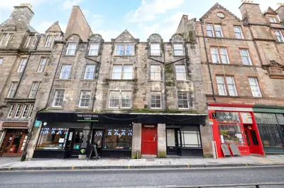 a large brick building with red doors on a street at JOIVY Charming Home with Patio Nearby the Castle in Edinburgh