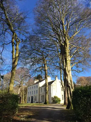 a white house with trees in front of it at Bonawe House Holiday Cottages in Taynuilt