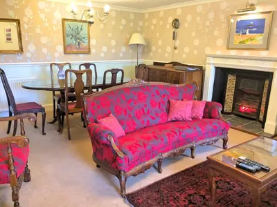 a living room with a red couch and a fireplace at Bonawe House Holiday Cottages in Taynuilt