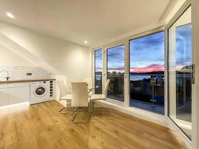 a kitchen with a table and chairs and large windows at The Penthouse in Oban