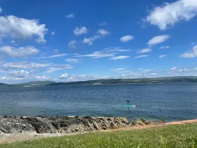 a person standing on a surfboard in the water at Dunoon River Clyde Flat in Innellan