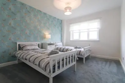 a bedroom with two beds and a window at Kilburn Holiday Cottage in Largs