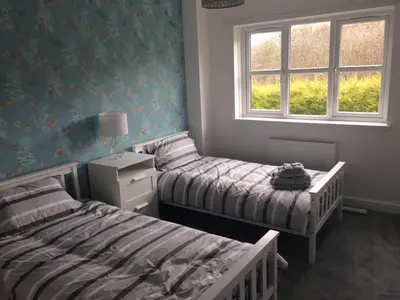 a bedroom with two beds and a window at Kilburn Holiday Cottage in Largs