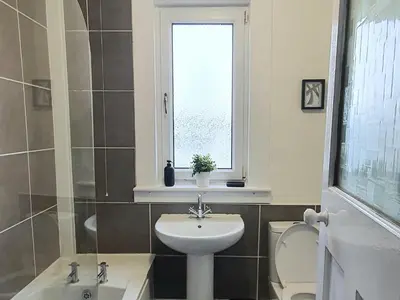 a bathroom with a sink and a toilet and a window at Large 3 Bed Apartment Glasgow West End Free Parking & Electric Vehicle point in Glasgow