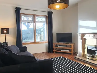 a living room with a couch and a television at Large 3 Bed Apartment Glasgow West End Free Parking & Electric Vehicle point in Glasgow