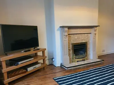 a living room with a tv and a fireplace at Large 3 Bed Apartment Glasgow West End Free Parking & Electric Vehicle point in Glasgow