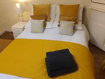 a bed with a yellow blanket and a black bag on it at Large 3 Bed Apartment Glasgow West End Free Parking & Electric Vehicle point in Glasgow
