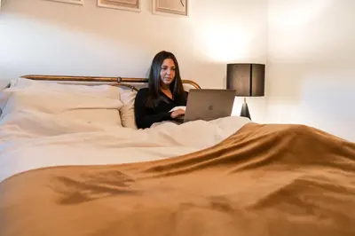 a woman laying in bed with a laptop at West End Escape - Prime Location in Glasgow