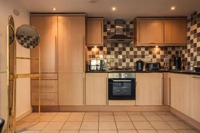 a large kitchen with wooden cabinets and appliances at City View - A Stunning 2 Bed Apartment in Glasgow