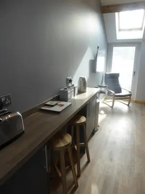 a kitchen with a counter and stools in a room at Auchendennan Farm Self Catering Cottages in Balloch