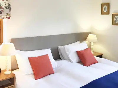 a bedroom with a white bed with two red pillows at The Wee House in Muthill