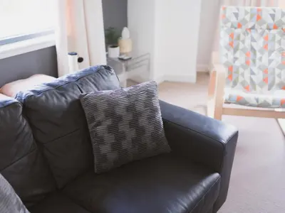 a black leather couch with a pillow on it at Lovely 2-Bed Flat Glasgow Harbour FREE parking - Pass the Keys in Glasgow